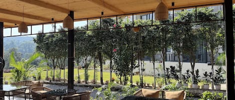 An outdoor seating area with tables and chairs, surrounded by potted plants and trees.