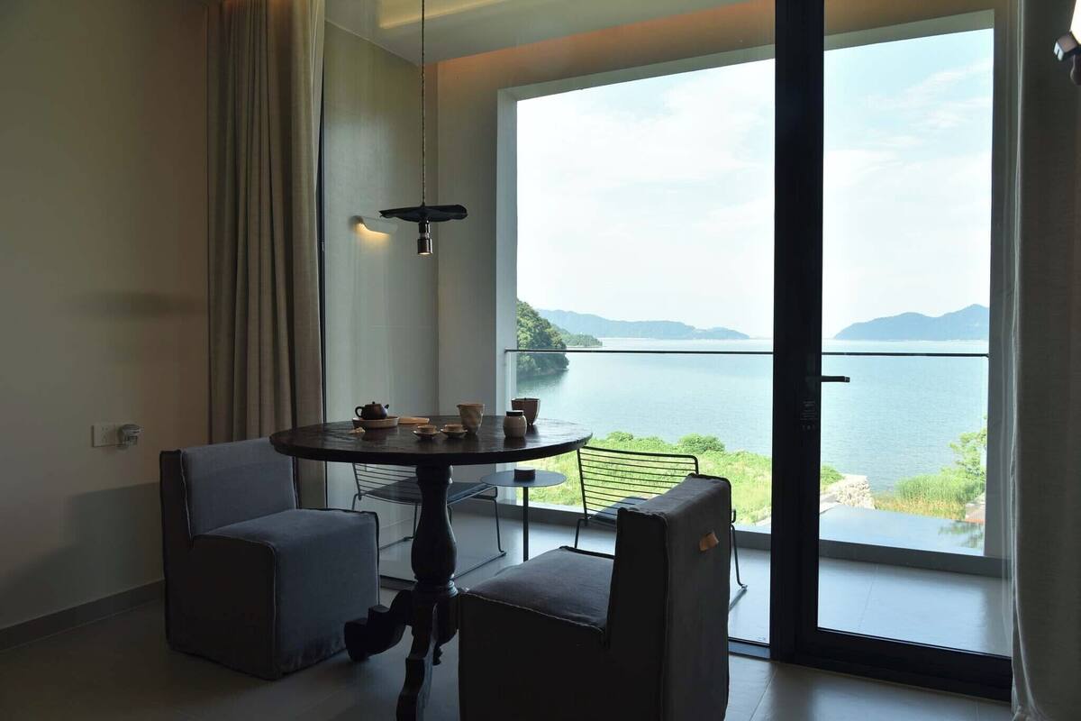 Ein Zimmer mit Tisch, Stühlen und Blick auf ein Gewässer, sowie einem Balkon.
