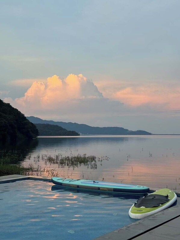 A swimming pool with a view of a calm lake and distant mountains. - Xiaoyao You Guesthouse Lushan West Sea (Jiujiang)