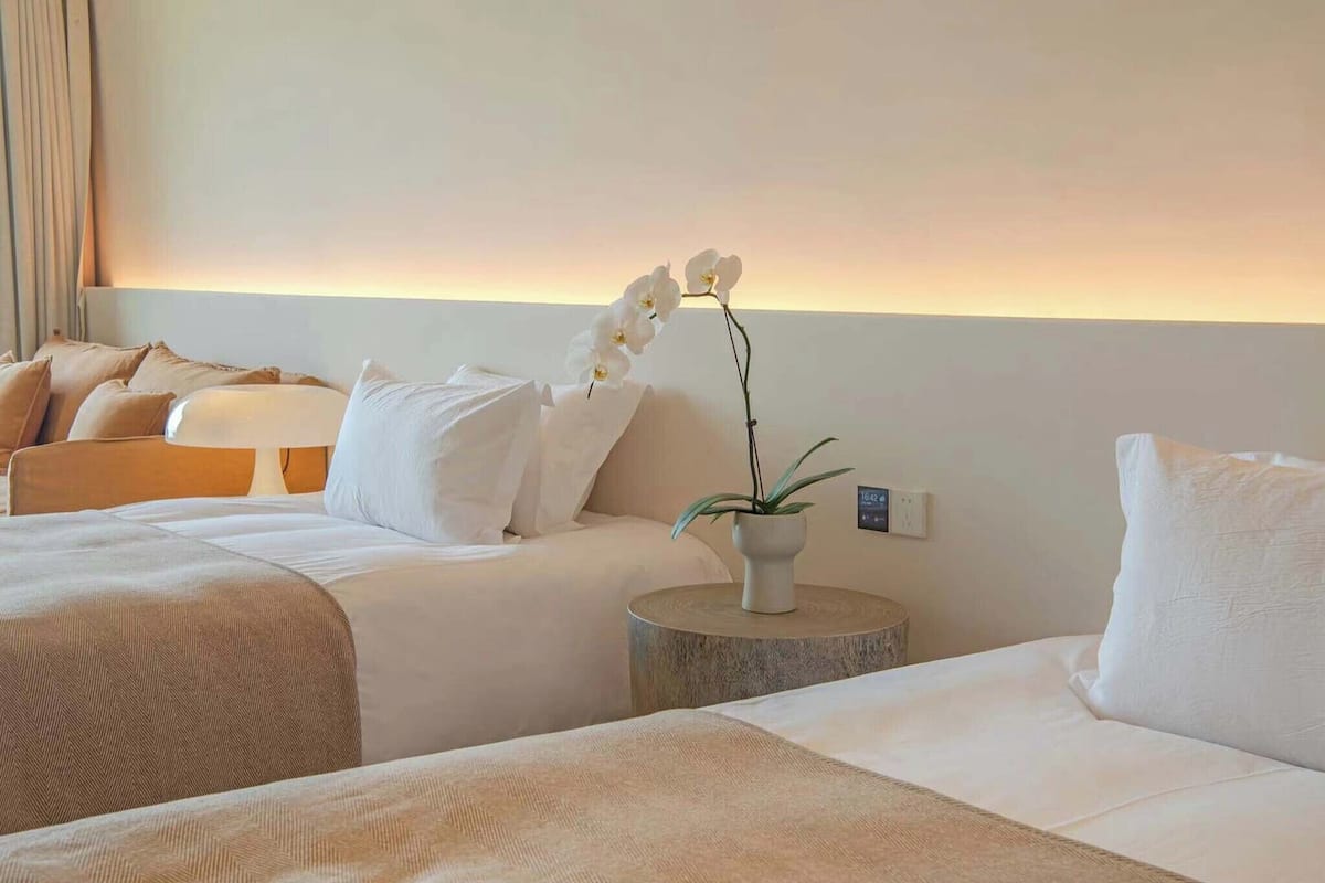 Ein Hotelzimmer mit zwei Betten, einem Nachttisch mit Pflanze und einer Wandleuchte.
