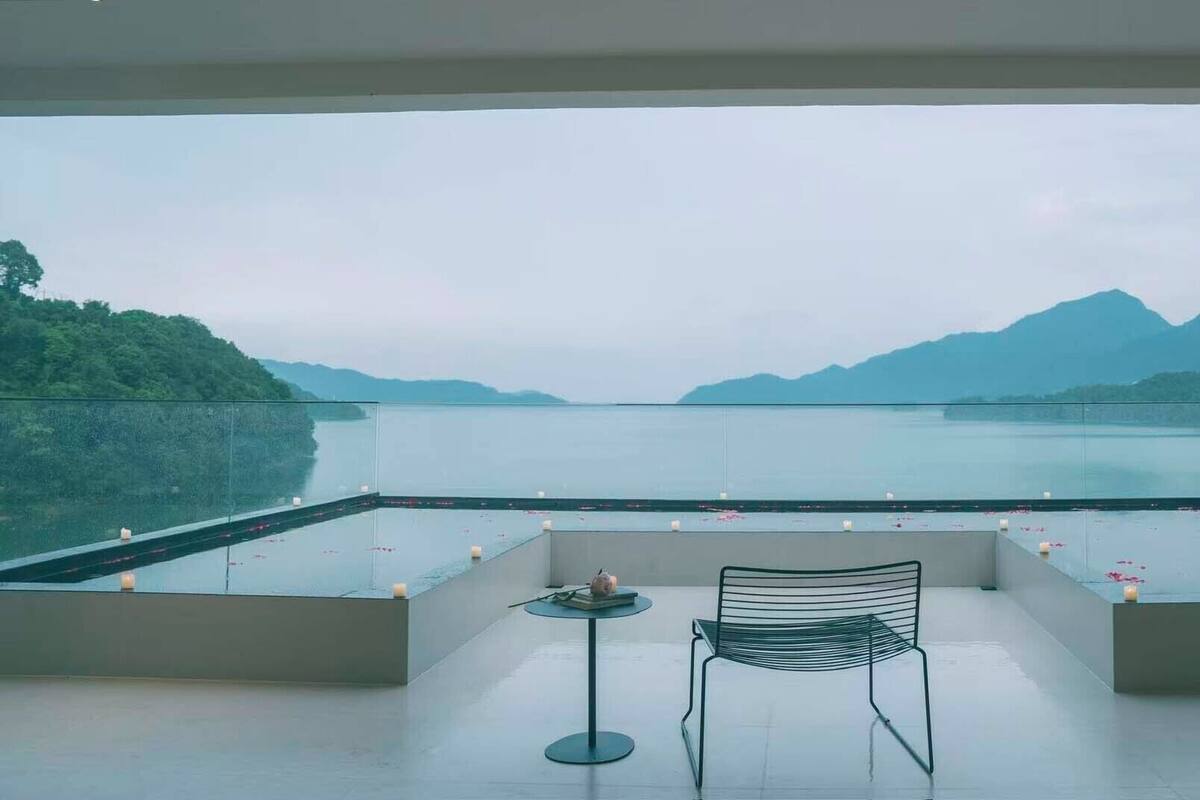 Ein Balkon mit Blick auf einen See und Berge, ein Stuhl und ein kleiner Tisch.