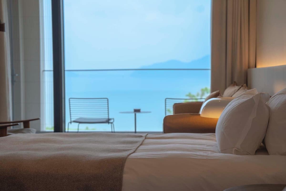 Ein Hotelzimmer mit einem großen Bett, Meerblick, einem kleinen Tisch und einem Sessel.