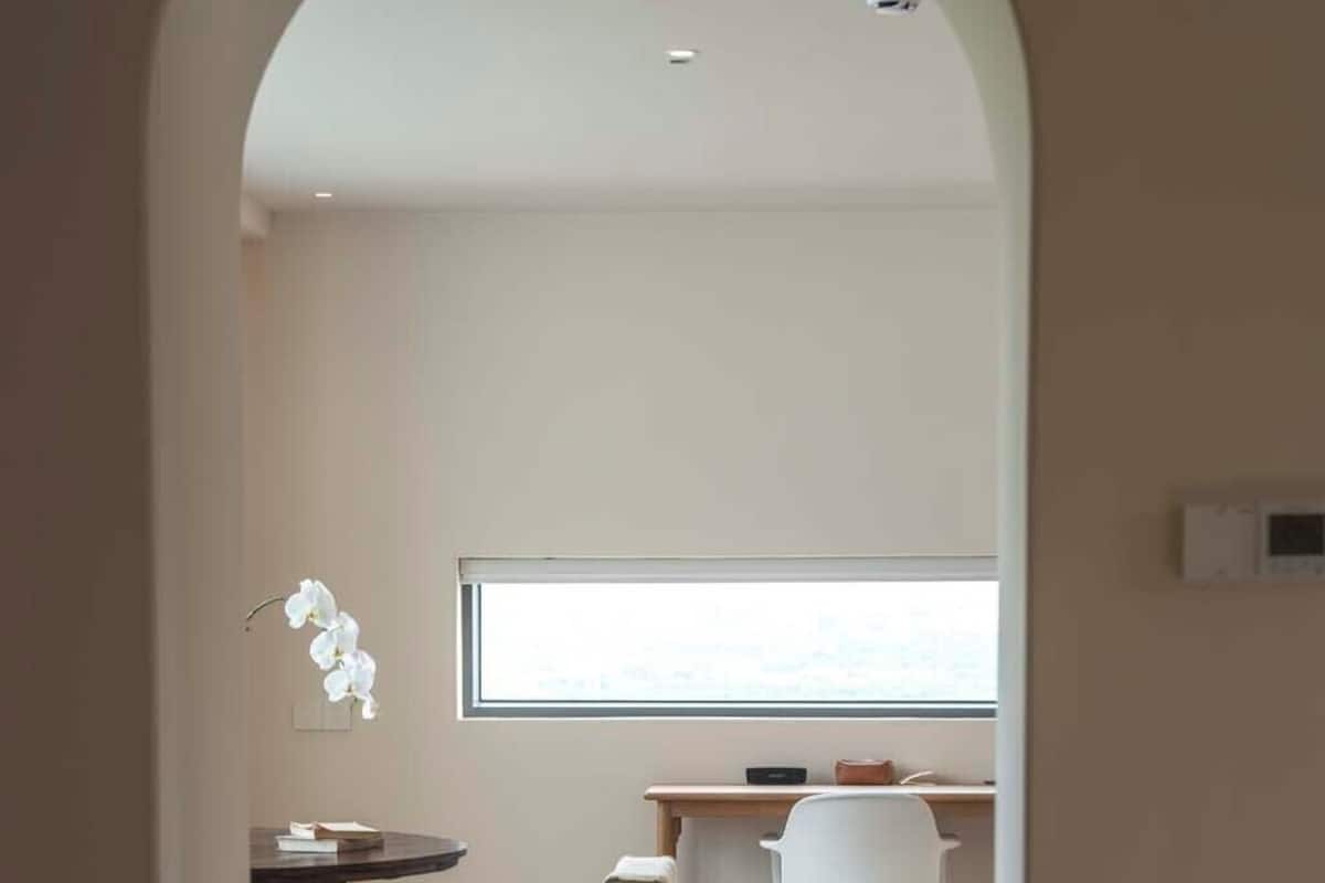 Ein modernes Interieur mit Essbereich, einem weißen Stuhl, einem kleinen Tisch und einem Fenster, das natürliches Licht hereinlässt.