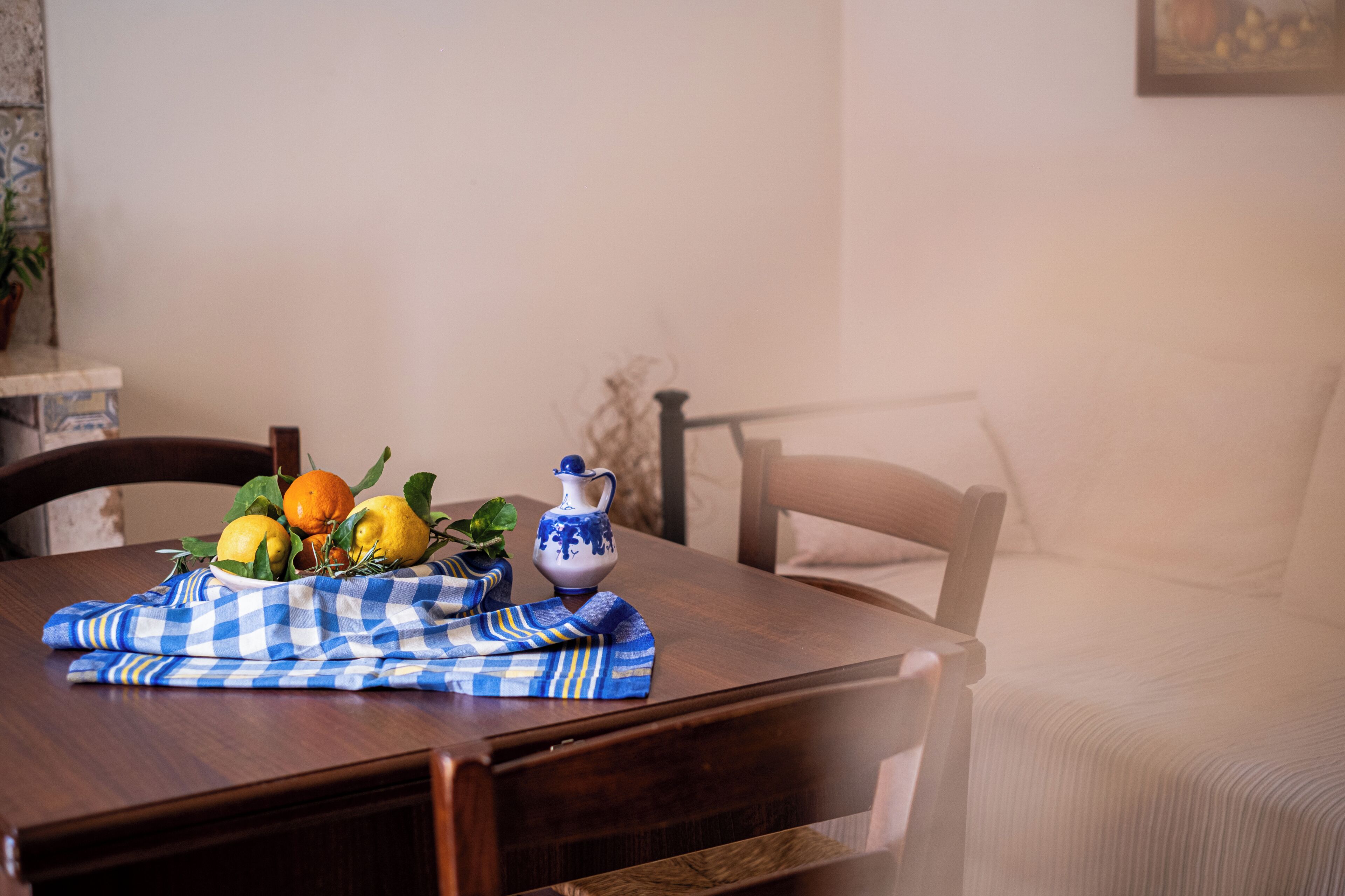 A dining table with a checkered tablecloth, a pitcher, and fruits.