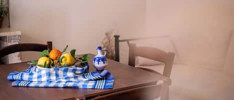 Une table à manger recouverte d’une nappe à carreaux, avec une carafe et des fruits.