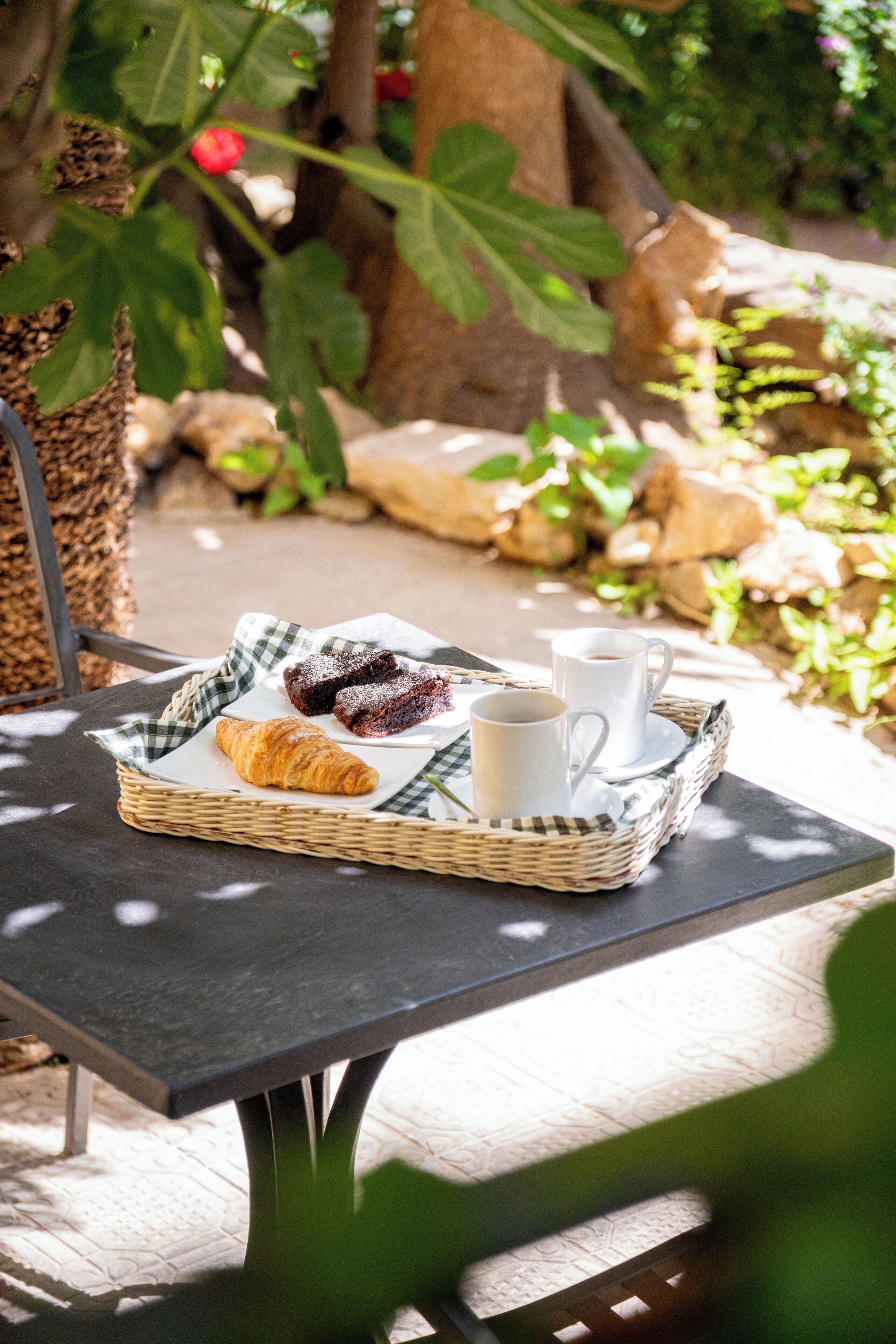 Una bandeja con pasteles y una taza sobre una mesa al aire libre.