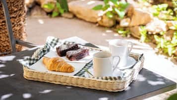 Una bandeja con pasteles y una taza sobre una mesa al aire libre.