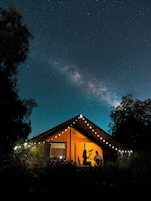 Una casa con un telescopio all'esterno, sotto un cielo stellato.