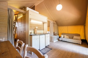 Una camera da letto mansardata accogliente con soffitto in legno, un letto a scomparsa, un angolo cottura e una zona pranzo con sedie.