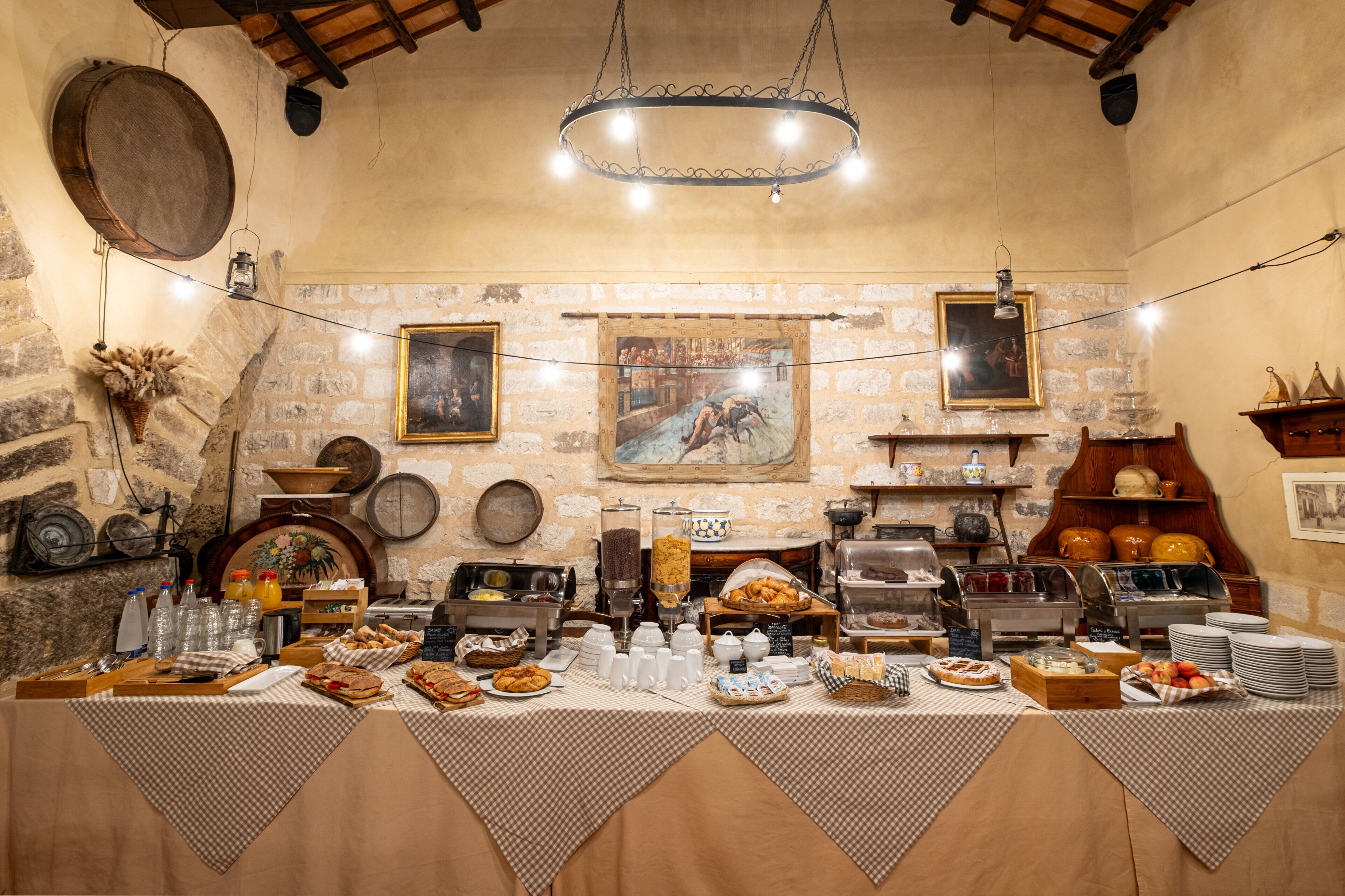 A breakfast buffet with various food items and a rustic interior with stone walls and artwork.