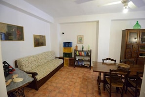 A living room with a sofa, a dining table with chairs, a bookshelf, and a cabinet. - Agriturismo Duca di Castelmonte (Trapani)