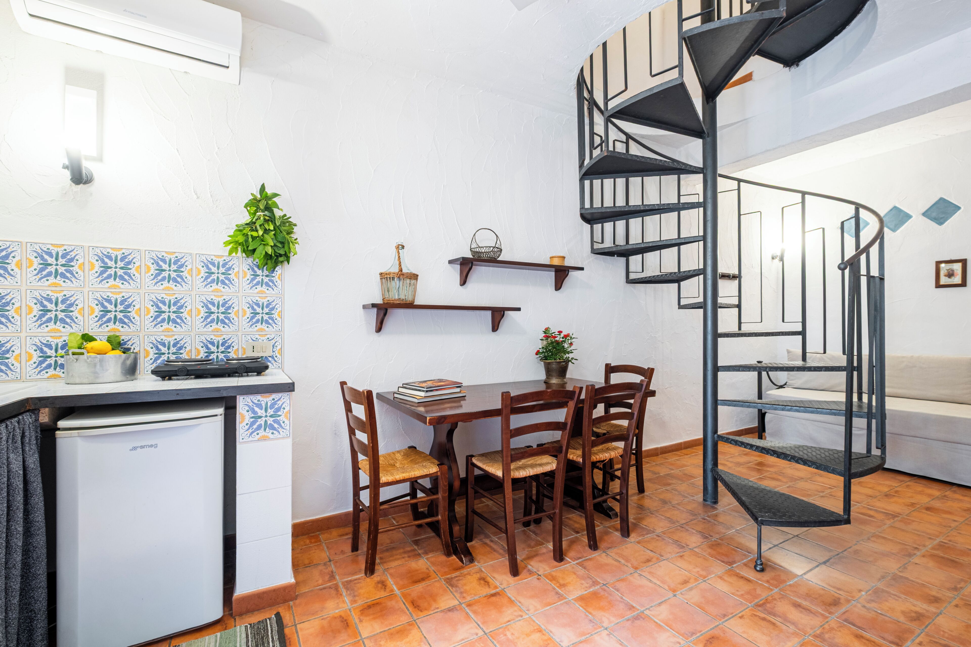 Cozinha compacta com área de refeições, pequena geladeira, fogão e mesa de jantar com cadeiras.