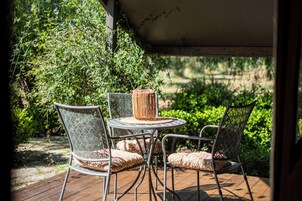 Una terrazza esterna con un tavolo rotondo e due sedie, immersa nel verde.