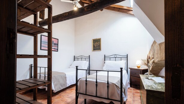 A bedroom with a wooden bunk bed, two single beds, a nightstand with a lamp, and a painting on the wall. - Agriturismo Duca di Castelmonte (Trapani)
