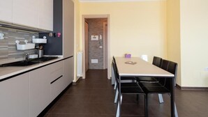Una cucina moderna con zona pranzo, che include un tavolo lungo e sedie, forno integrato e microonde.