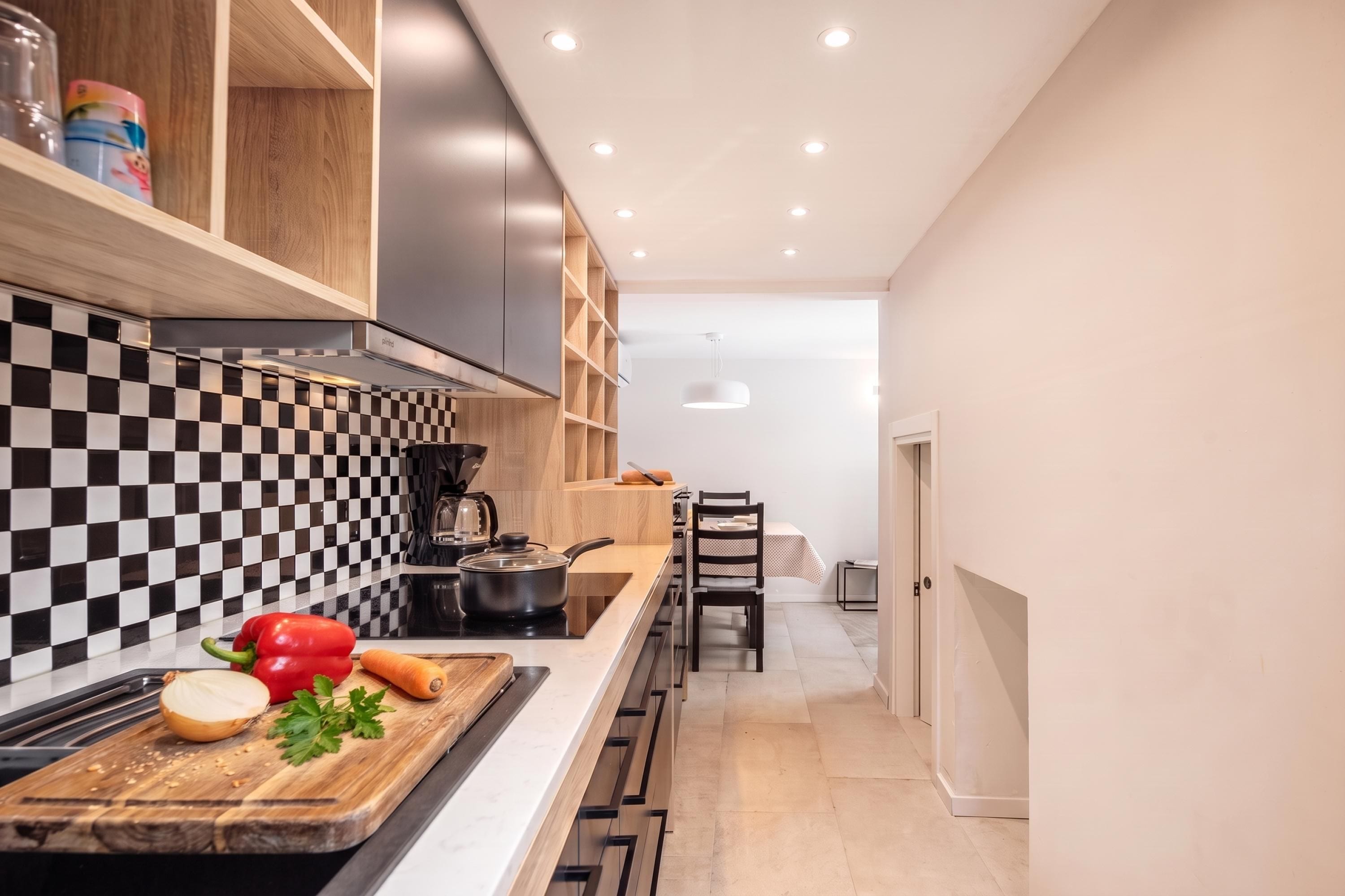 A modern kitchen with a black and white checkered backsplash, a wooden countertop, and a dining area with a table and chairs.