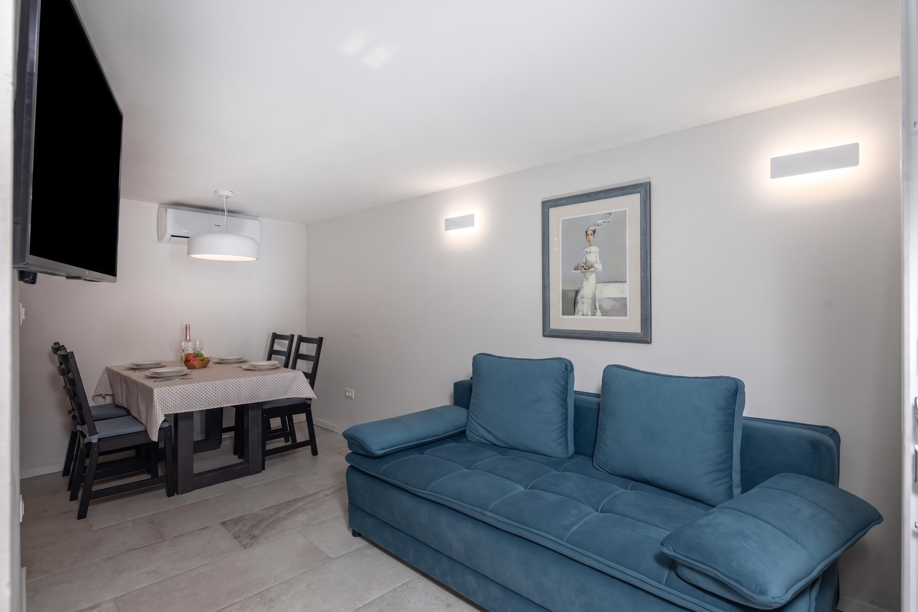 A compact living space with a dining area, a sofa, and a wall-mounted air conditioning unit.