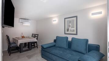 A compact living space with a dining area, a sofa, and a wall-mounted air conditioning unit.