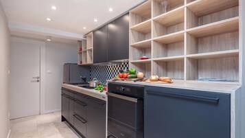 A modern kitchen with dark cabinetry, a checkered backsplash, and a variety of fresh produce on the counter.