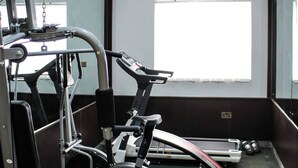 A gym with exercise equipment, a treadmill, and a large window. - MBL HOTEL  (Alakahia)