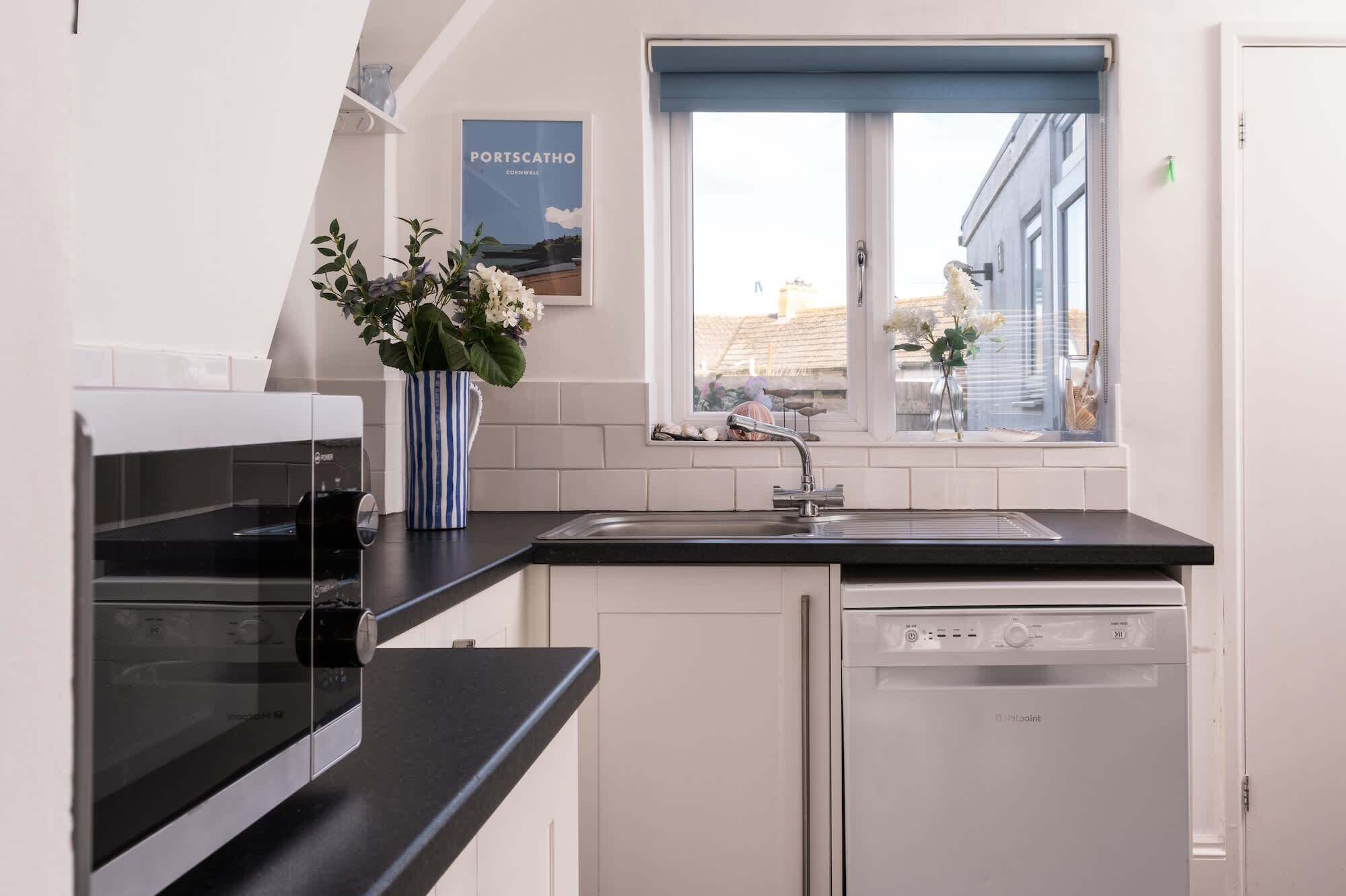 Eine moderne Küche mit Geschirrspüler, Spüle und einem Fenster mit Aussicht.