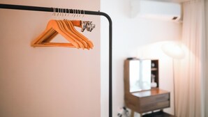 A hotel room with a wooden hanger on a black metal rack, a bedside table with a lamp, and a mirror. - JS building- 505 (Seoul)