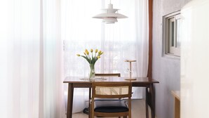 A dining area with a table, chairs, a vase of flowers, and a hanging light fixture. - JS building- 505 (Seoul)
