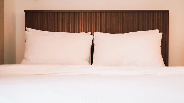A bed with a wooden headboard, two pillows, and a plain white bedspread. - JS building- 505 (Seoul)