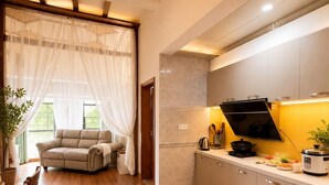 A modern kitchen with wooden flooring, a sofa, and a dining area with a table and chairs. - Han Exotic inn (Zhangjiajie)