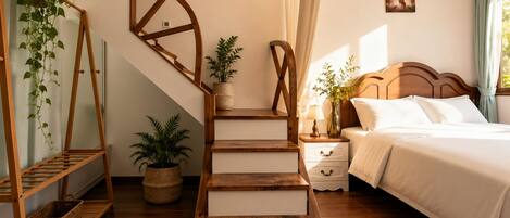 A bedroom with a wooden staircase, a bed with white bedding, a nightstand with a lamp, and a wall-mounted picture.