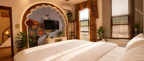 Una camera da letto con un letto grande, una TV montata su una parete decorativa, una finestra con tende e una scala.