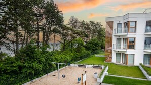 A modern building with a rooftop garden, a volleyball net, and a sandy play area. - Melia | Taras, Plaża, Widok i Relaks | SPA (Gąski)