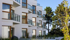 A multi-story residential building with balconies, large windows, and a landscaped garden. - Melia | Taras, Plaża, Widok i Relaks | SPA (Gąski)