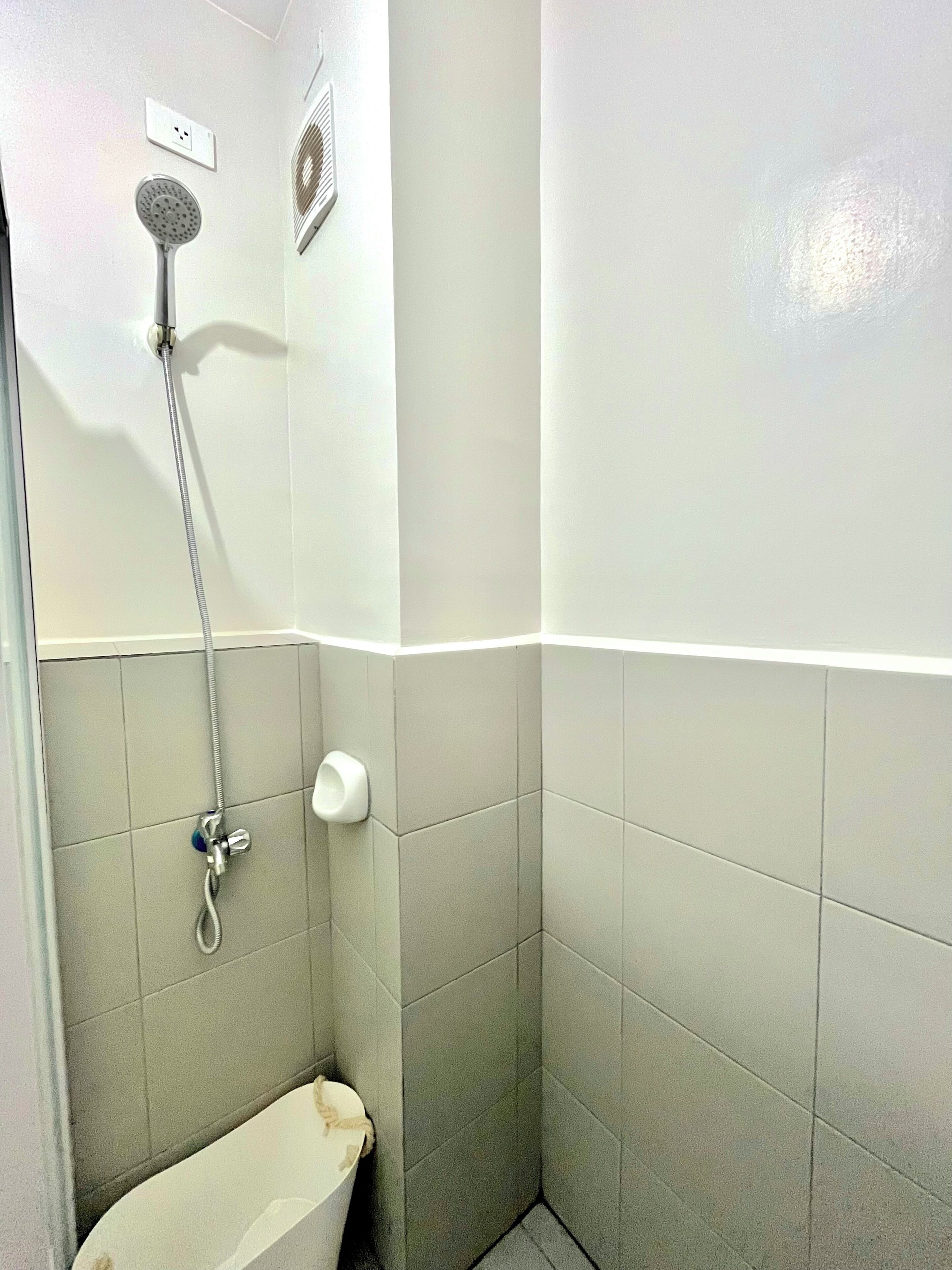 A small bathroom with a shower, toilet, and a towel rack.