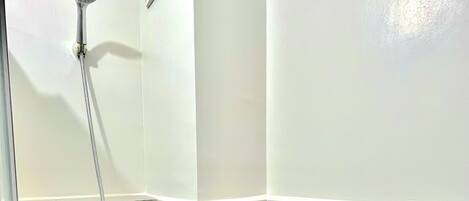 A small bathroom with a shower, toilet, and a towel rack.