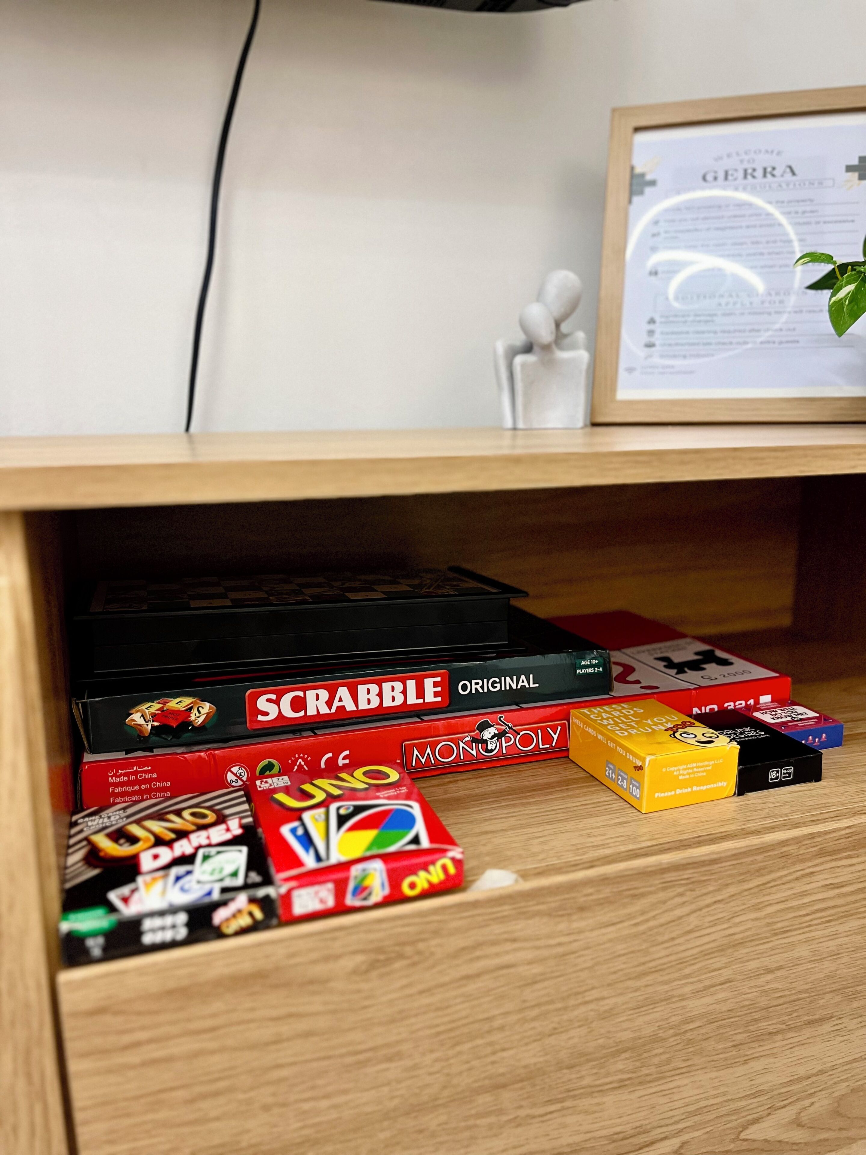 Una estantería con diversos juegos de mesa, como Scrabble, UNO y Monopoly.