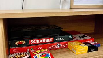 Una estantería con diversos juegos de mesa, como Scrabble, UNO y Monopoly.
