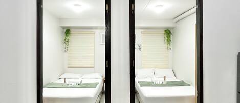 A mirrored room with a bed, a window with blinds, and a plant.