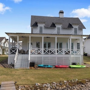 A two-story white house with a covered porch, a chimney, and a small outdoor seating area.