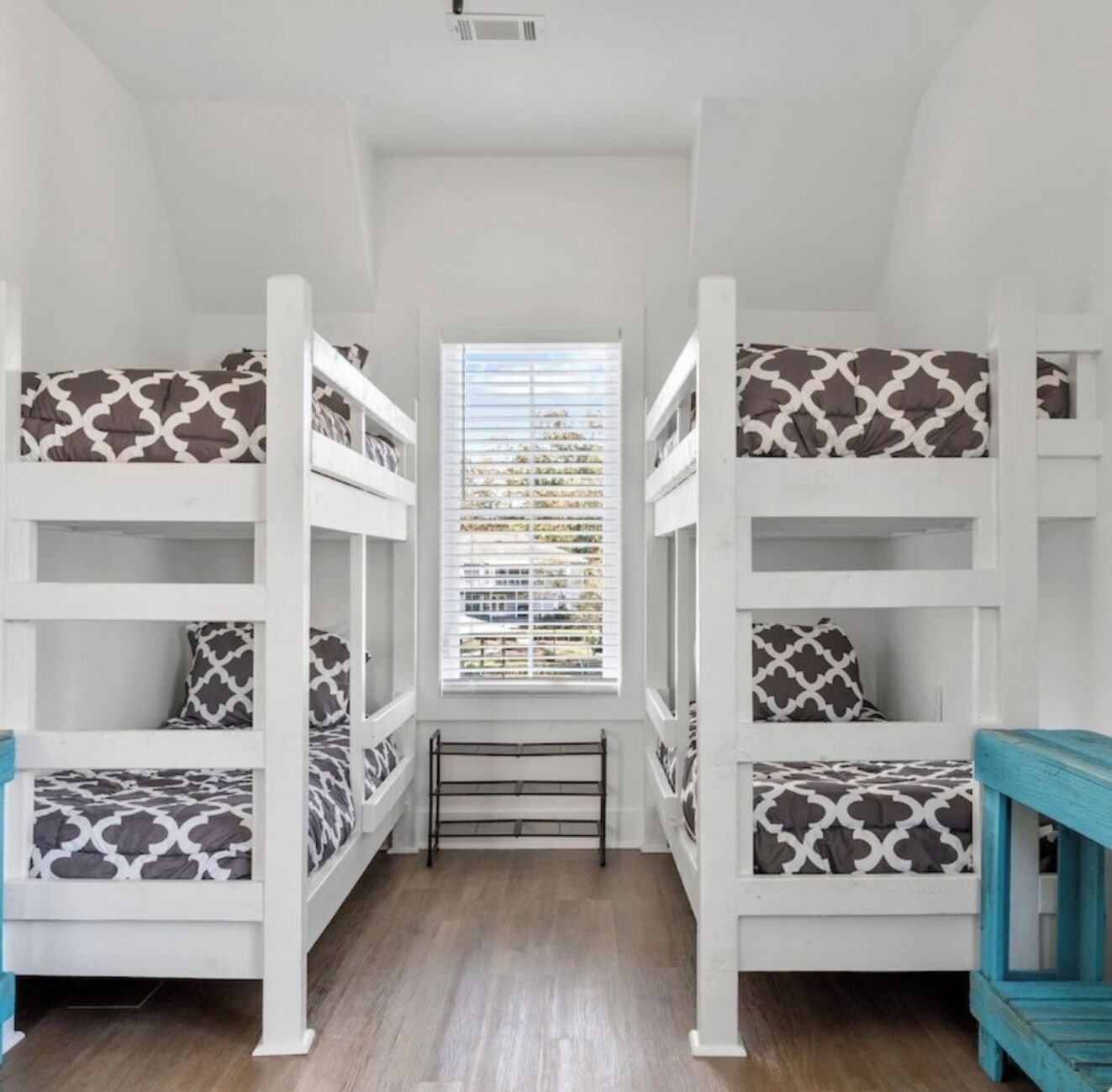 Una habitación con literas, una ventana con persianas y suelo de madera.