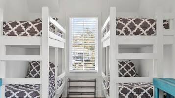 Una habitación con literas, una ventana con persianas y suelo de madera.