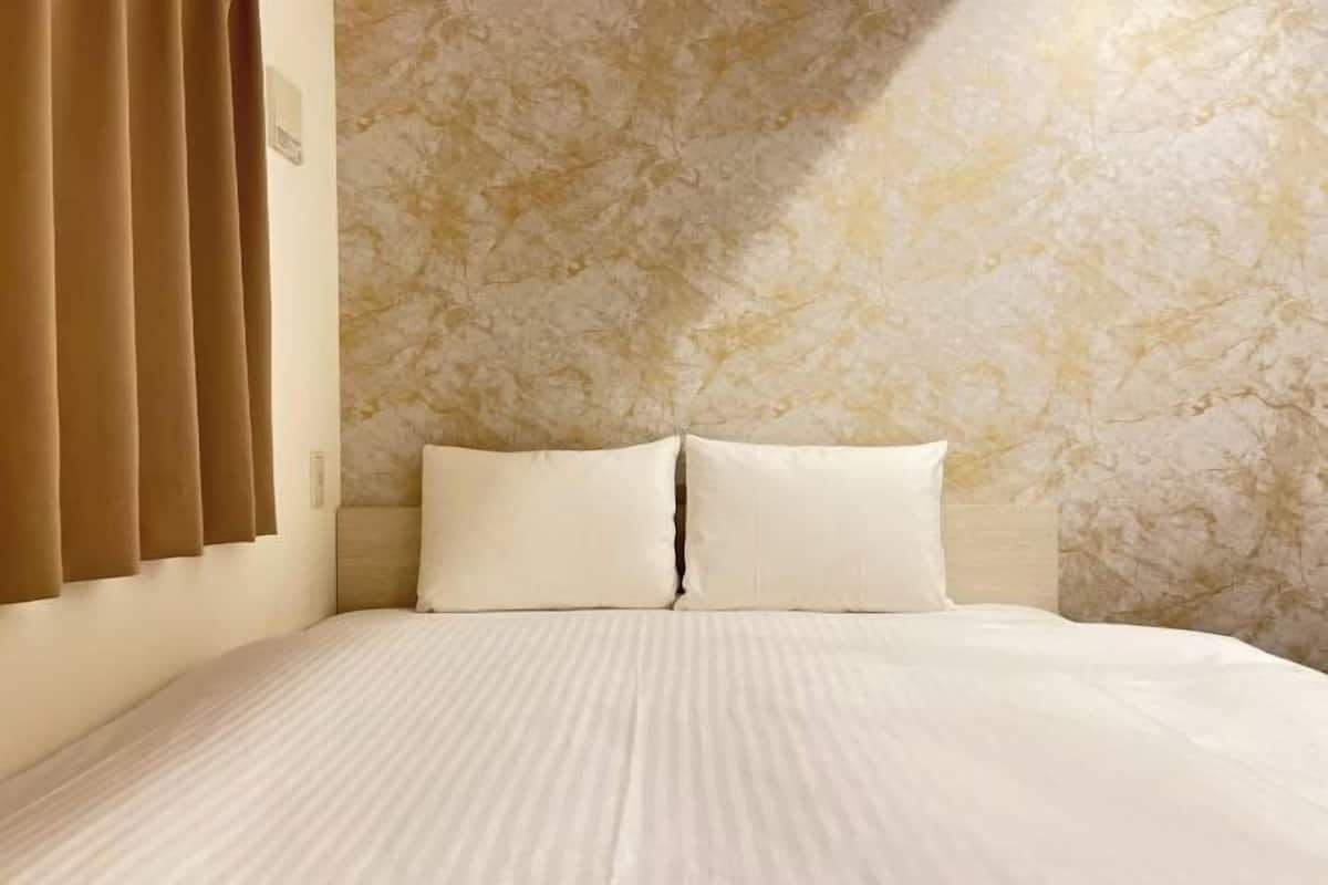 A bed with a textured wall behind it.