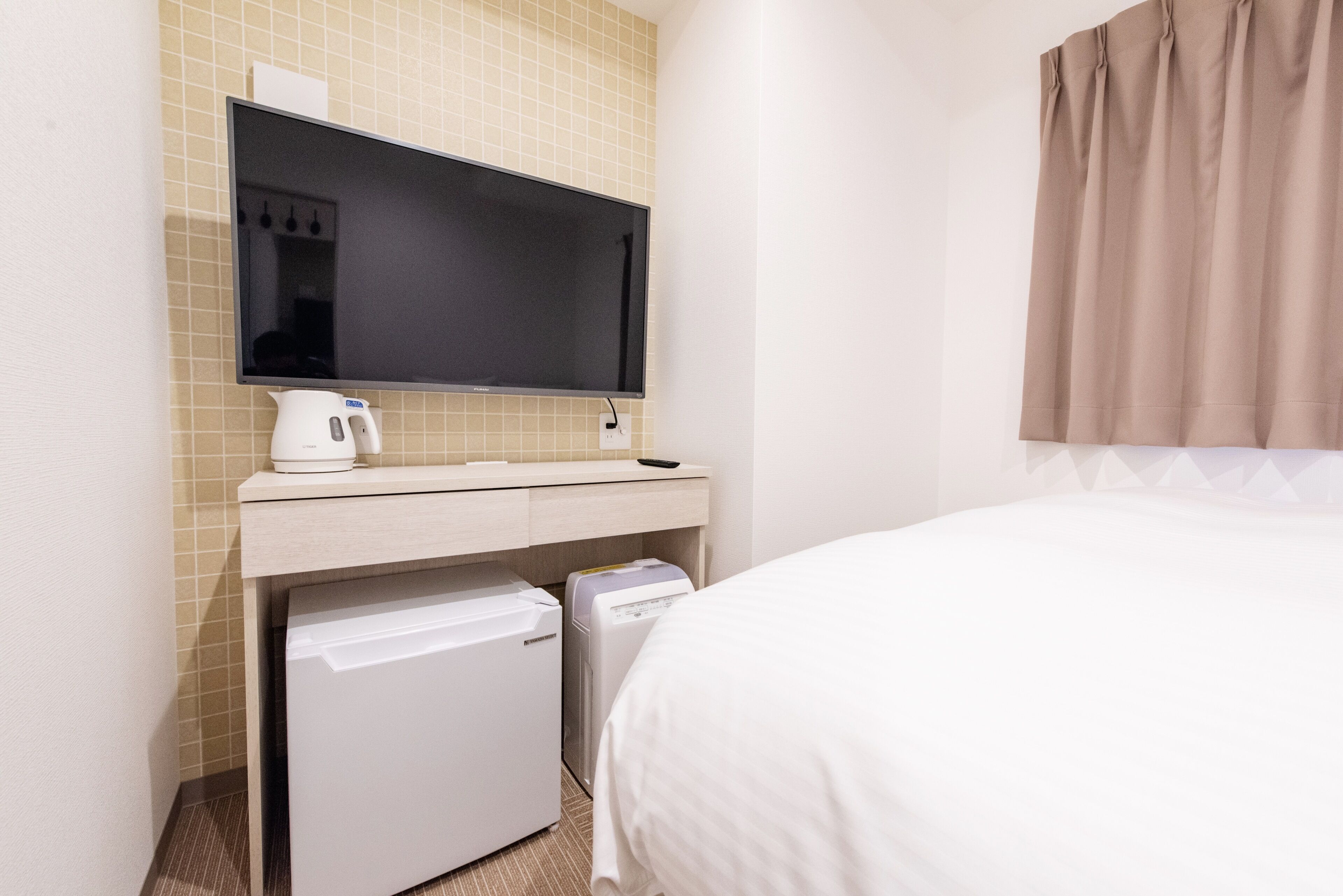 Une chambre d’hôtel équipée d’un lit, d’un téléviseur fixé au mur, d’un petit réfrigérateur et d’un four à micro-ondes.
