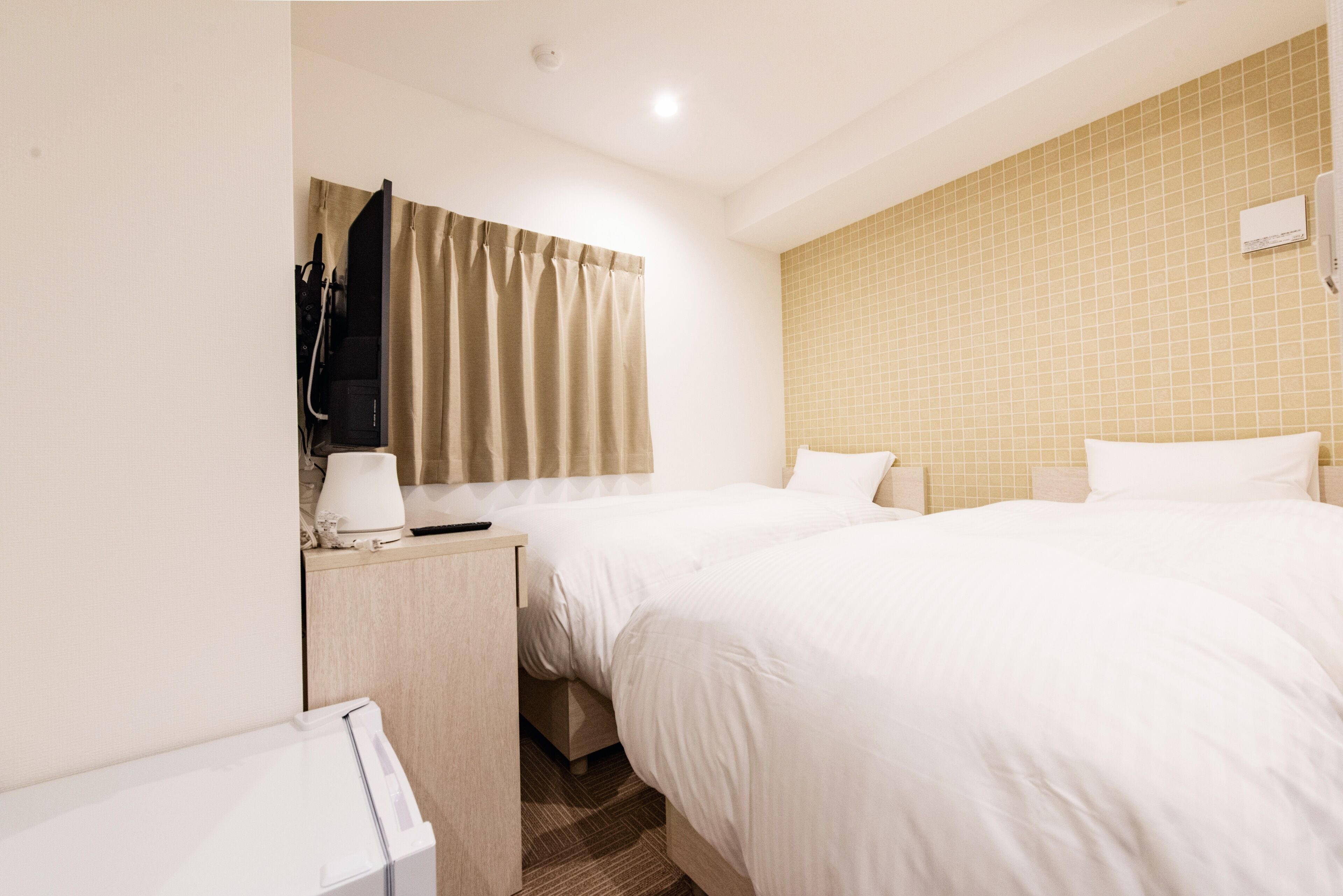 A hotel room with two beds, a desk, a TV, and a bathroom.