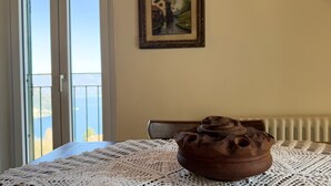 Une pièce avec une table recouverte d’une nappe tissée, un pot en argile rustique et un tableau encadré accroché au mur.