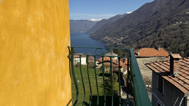 Un balcon avec vue sur un lac, des montagnes et un village.