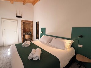 A hotel room with a bed, a desk, a chair, and a stone wall. - Isula Antica (Floridia)