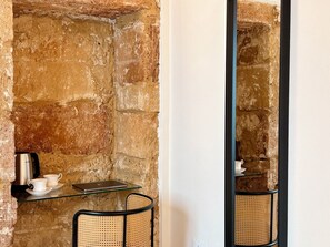 A rustic stone wall with a small table, a chair, a kettle, and a laptop. - Isula Antica (Floridia)