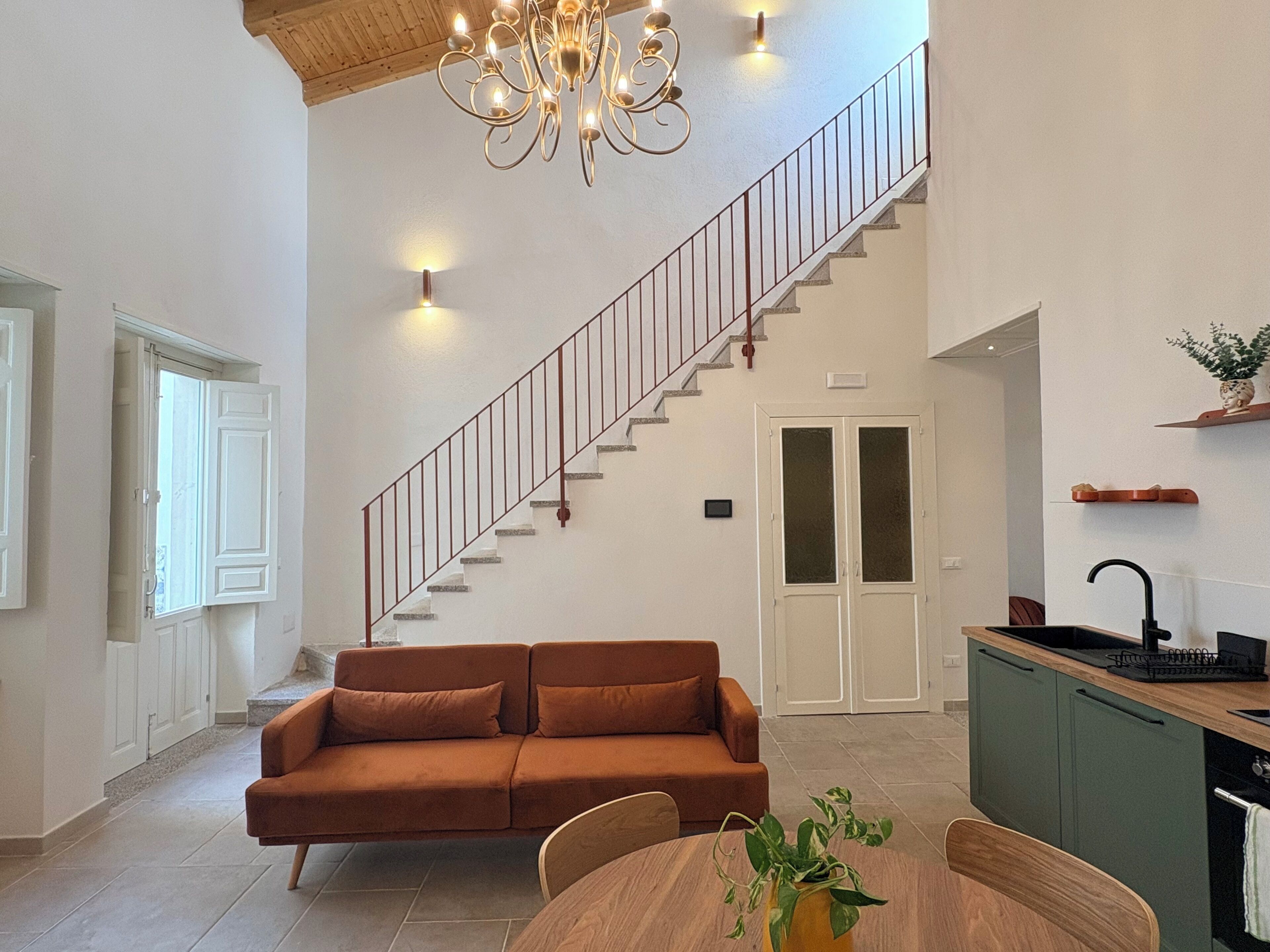 Un intérieur moderne comprenant un escalier, un canapé, une table à manger et un coin cuisine.