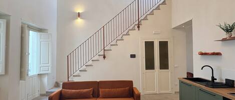 Un intérieur moderne comprenant un escalier, un canapé, une table à manger et un coin cuisine.